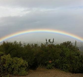 A rainbow is visible from the lookout at the top of the hiking trail.